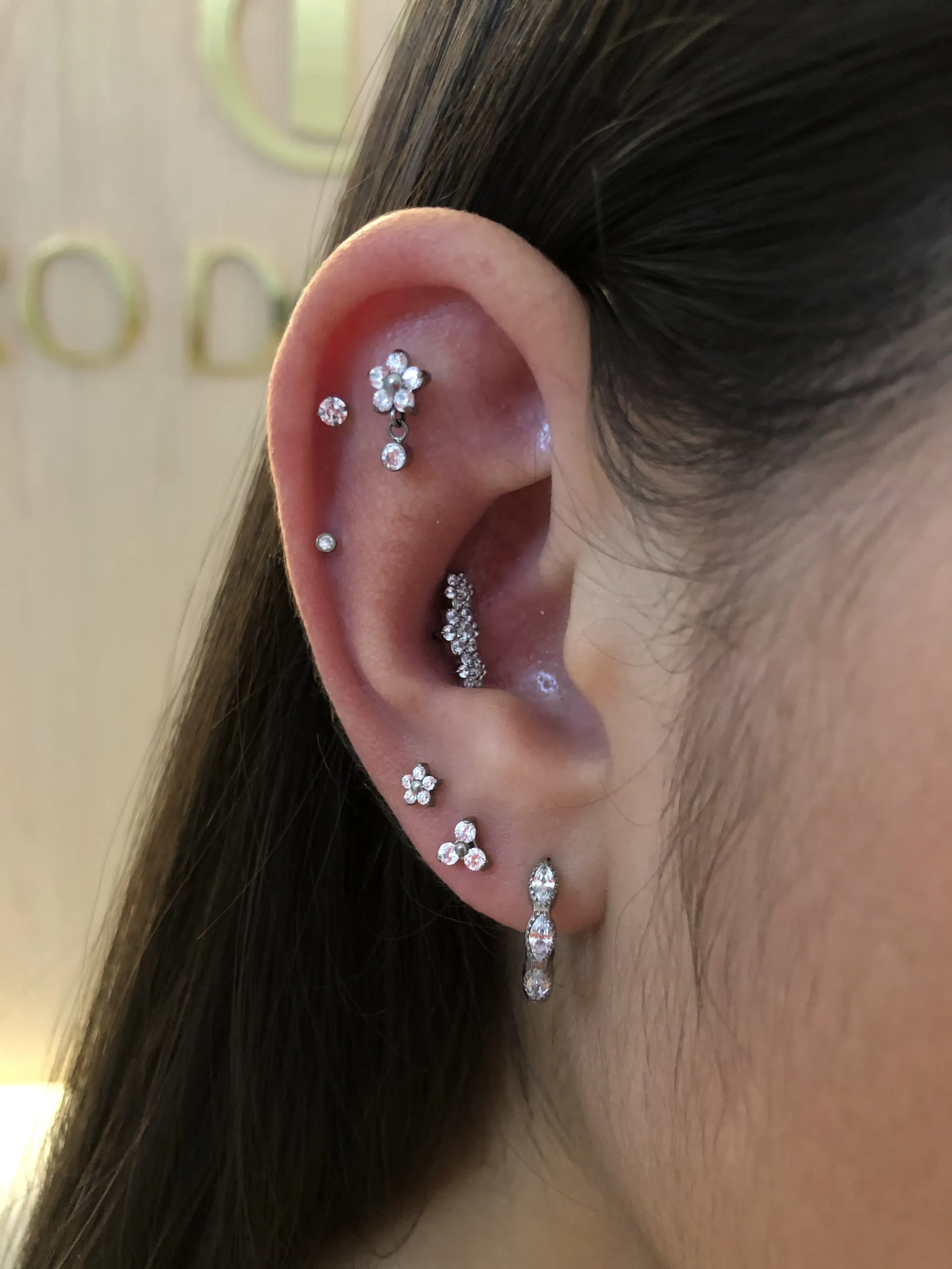 Orelha com vários piercings brilhantes na cartilagem e no lóbulo